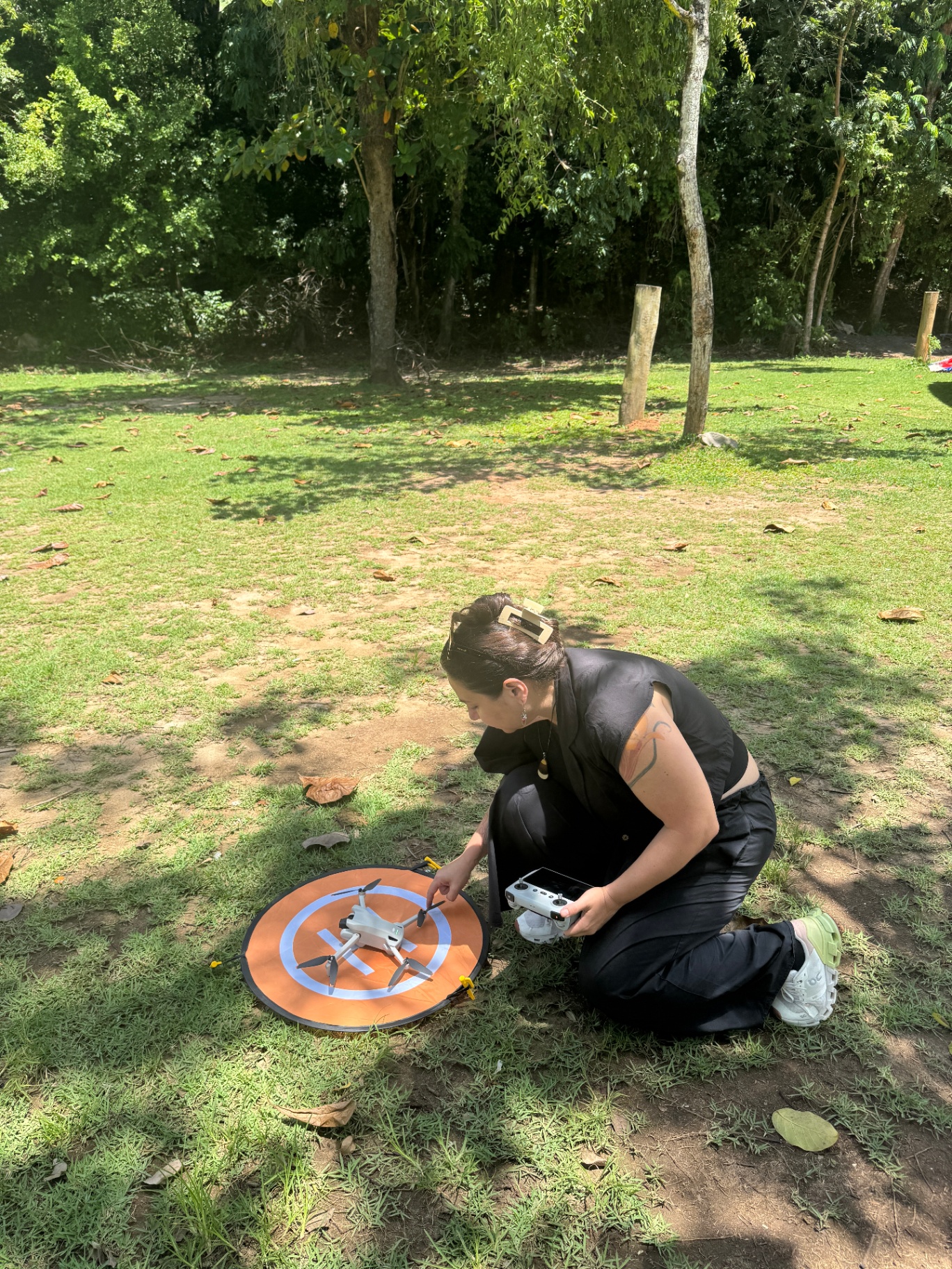 Aluna preparando drone no campo para atividade prática de voo